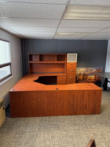Furnished office with large wood desk and shelves